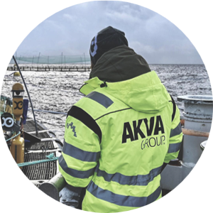 Employee in protective gear with AKVA logo standing at a sea-based aquaculture installation
